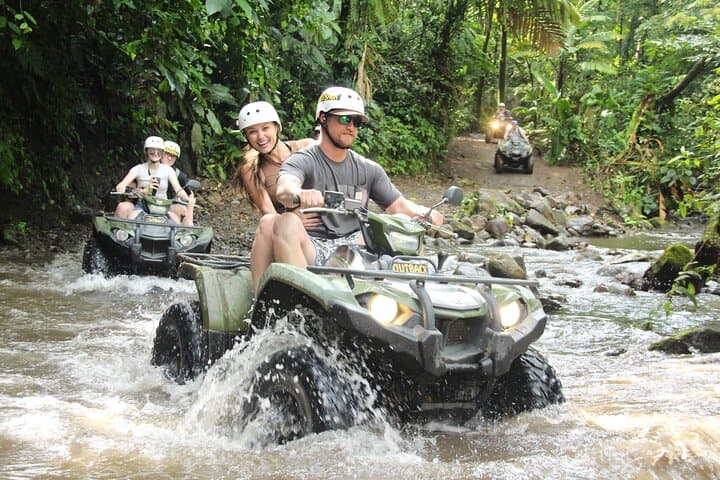 ATVs crossing a jungle river near the volcano